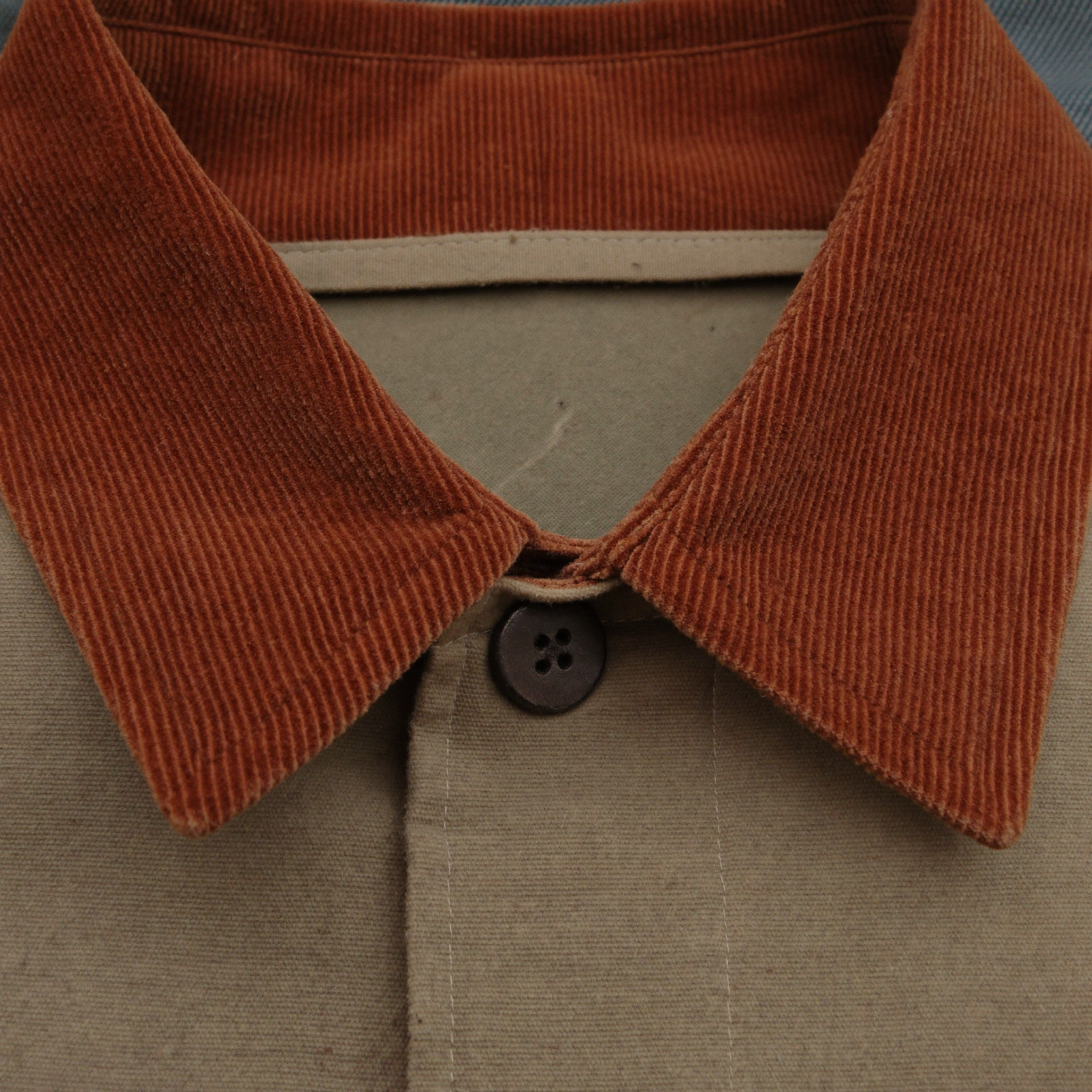 Close-up of a rust corduroy collar lying flat against tan cotton duck
